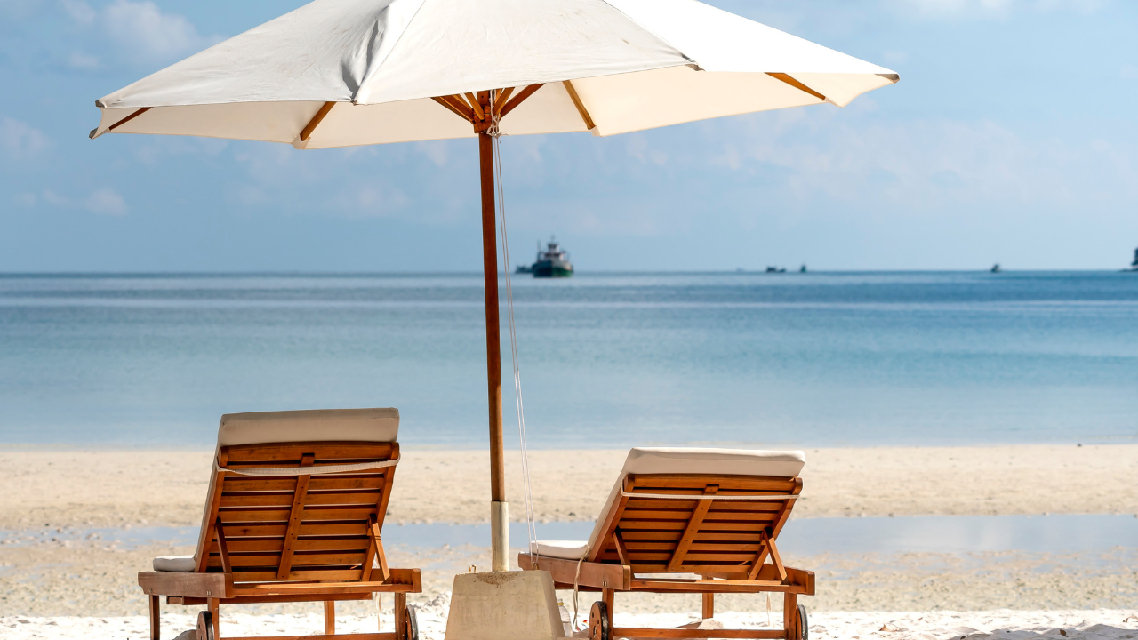 two beach chairs under an umbrella on a tranquil beach